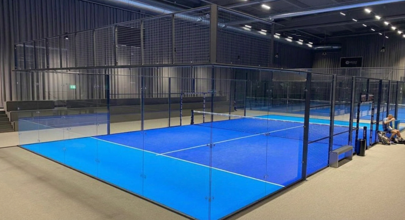 Indoor padel courts with blue surface and glass walls